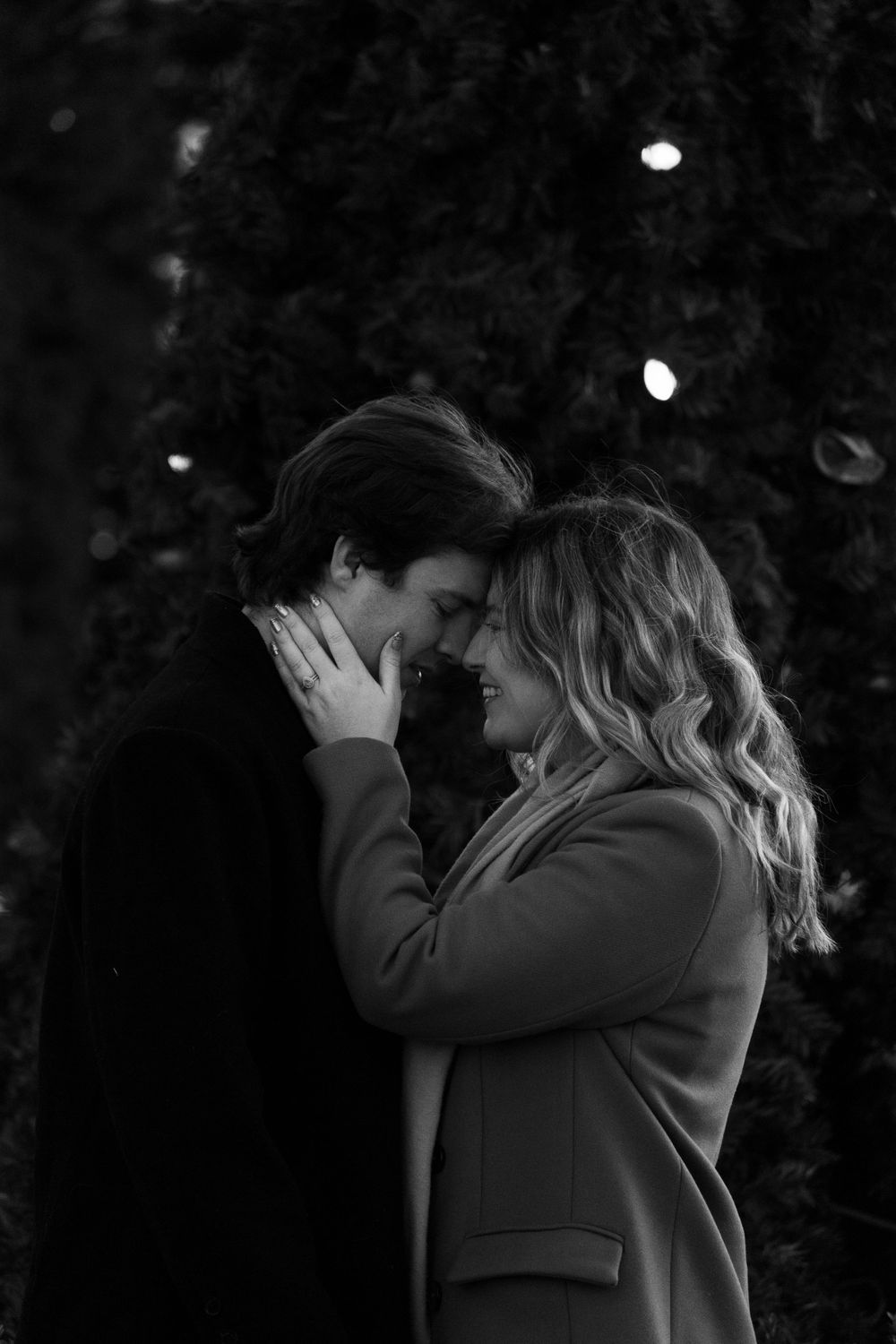 An intimate black and white portrait of a couple sharing a tender moment.