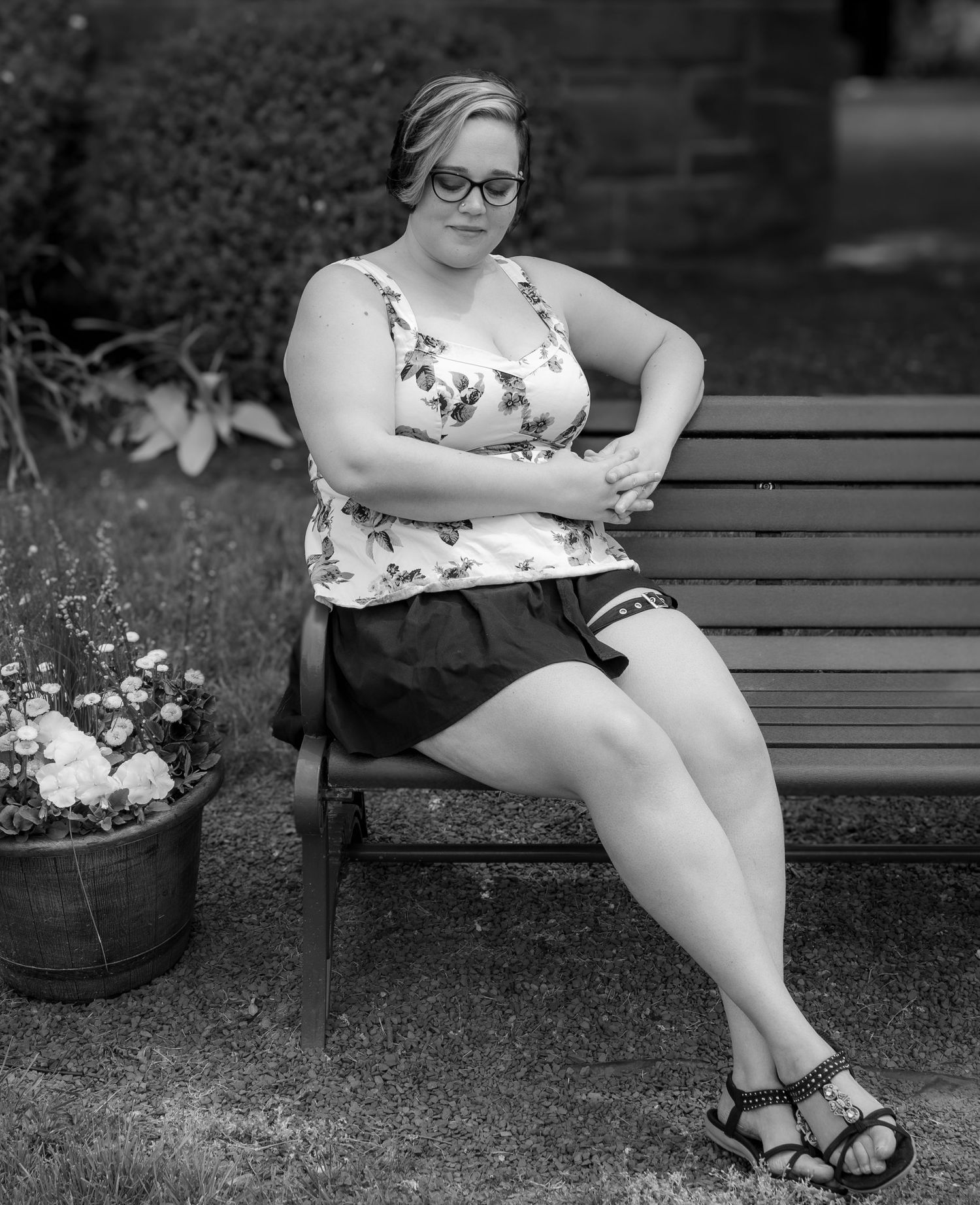 Black and white portraits of someone sitting on park bench with flowers nearby.