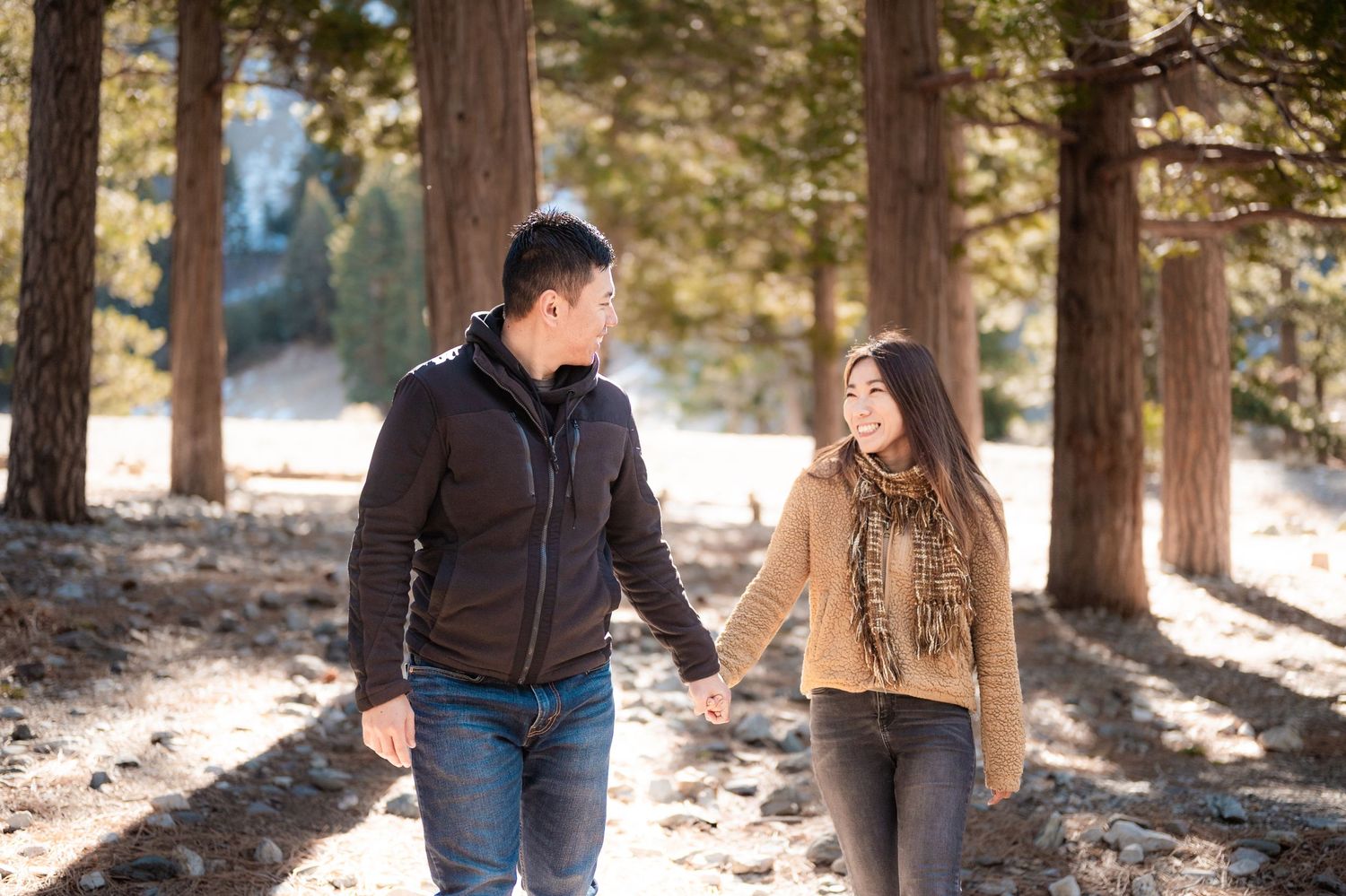 A couple walks together on a snowy forest path during winter.
