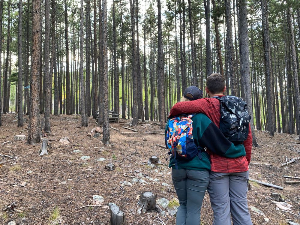 Couple standing side by side facing away from camera in Colorado Mountains