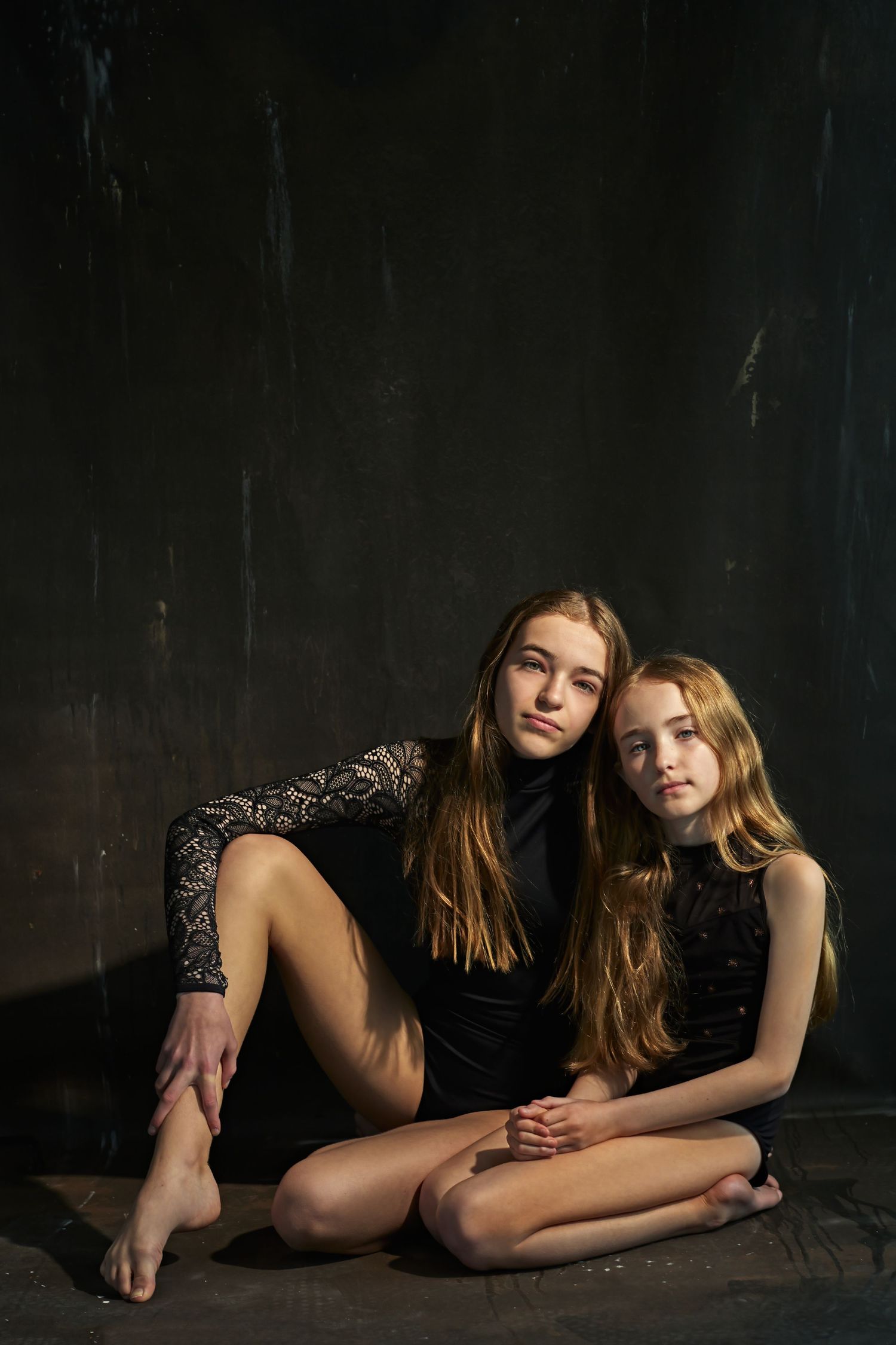 Artistic black and white portrait series showing intimate poses on dark floor.
