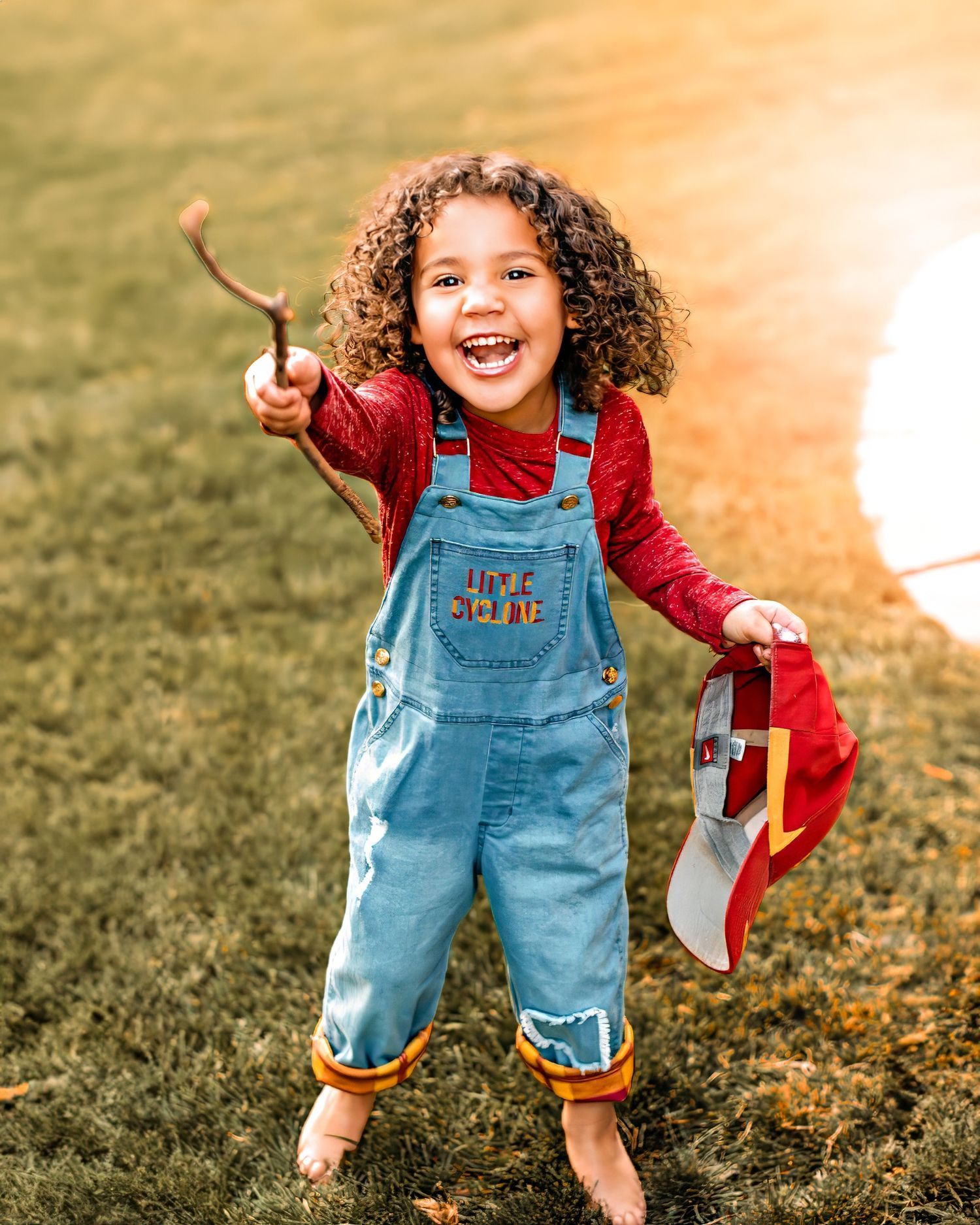 little girl with a wide open smile pointing a stick at the camera