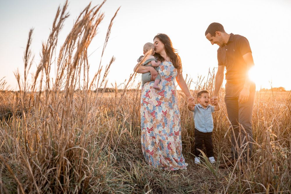 Family portrait featuring a mother, father, and two children standing together in a grassy field Melbourne Palm Bay Brevard County Florida