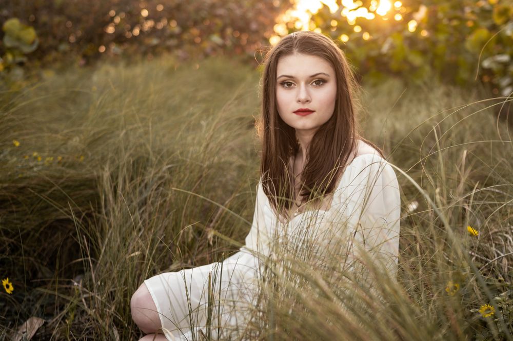 Senior girl photoshoot session sitting in grass in field at sunset Palm Bay Melbourne Cocoa Beach Vero Florida Brevard County