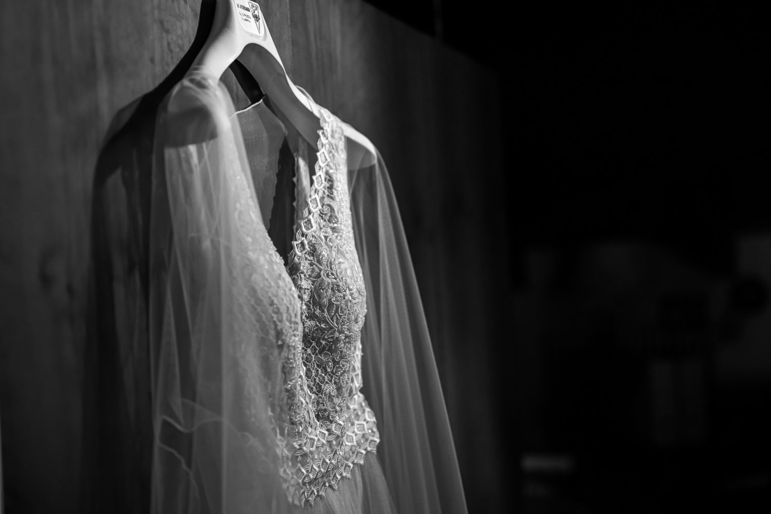 Detail shots of a wedding dress showing intricate lace and fabric textures in dramatic lighting.