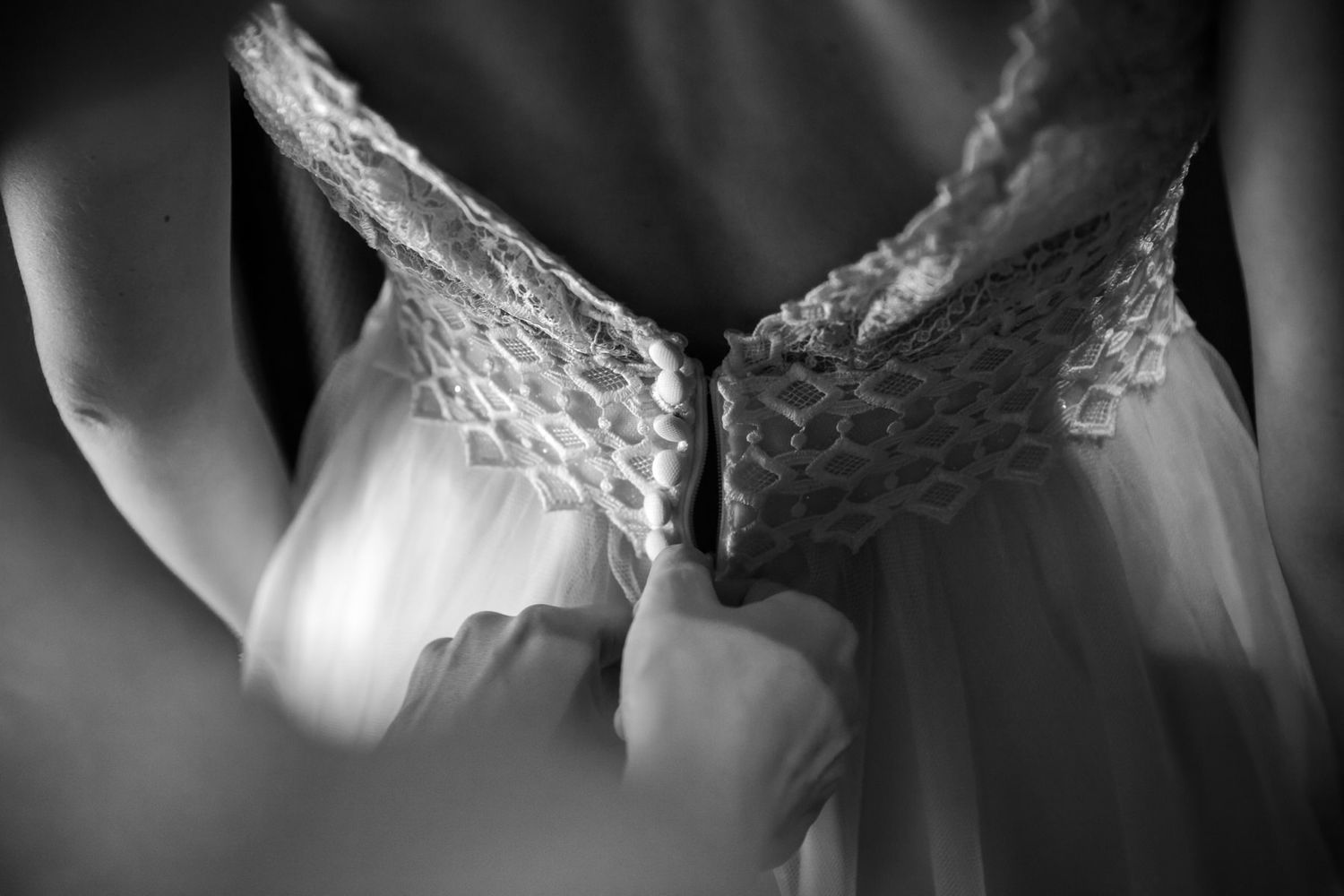 Close-up details of wedding dress lace and embellishments in black and white.