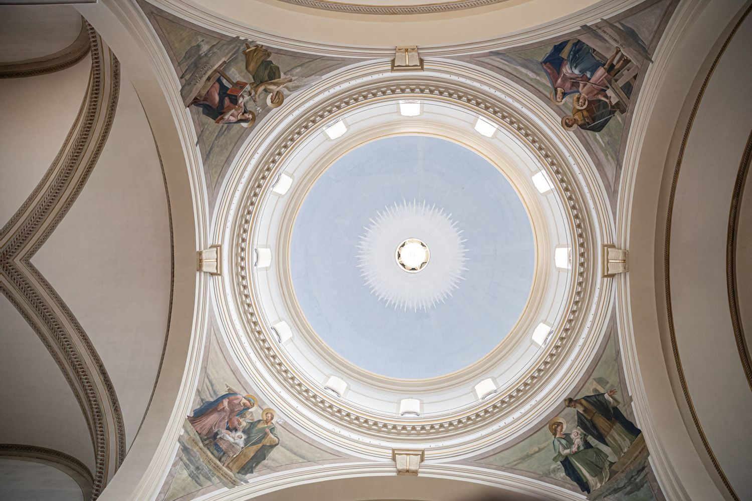Ornate church ceiling with circular dome and decorative architectural details.