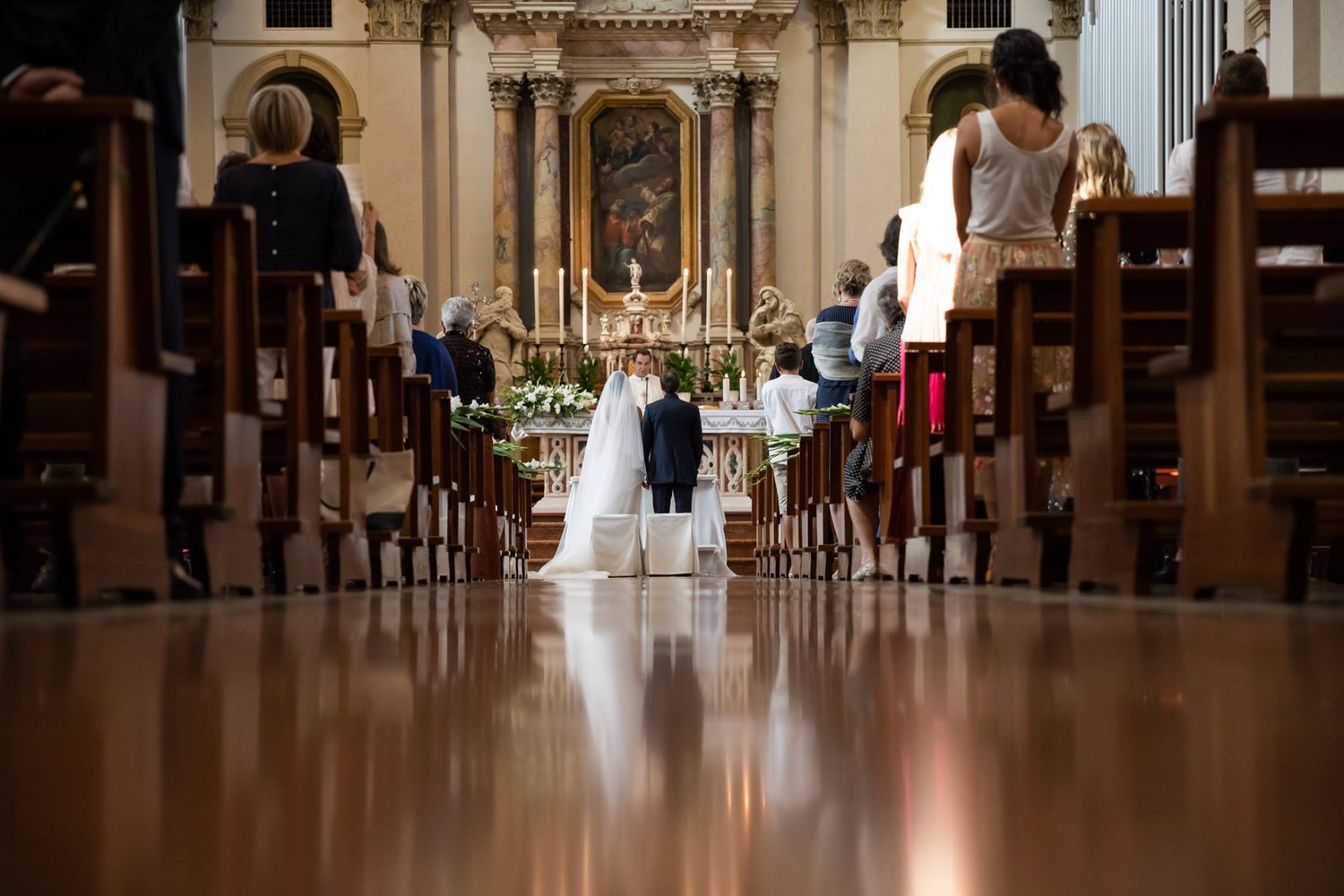 Church aisle view of wedding ceremony with ornate altar in background.