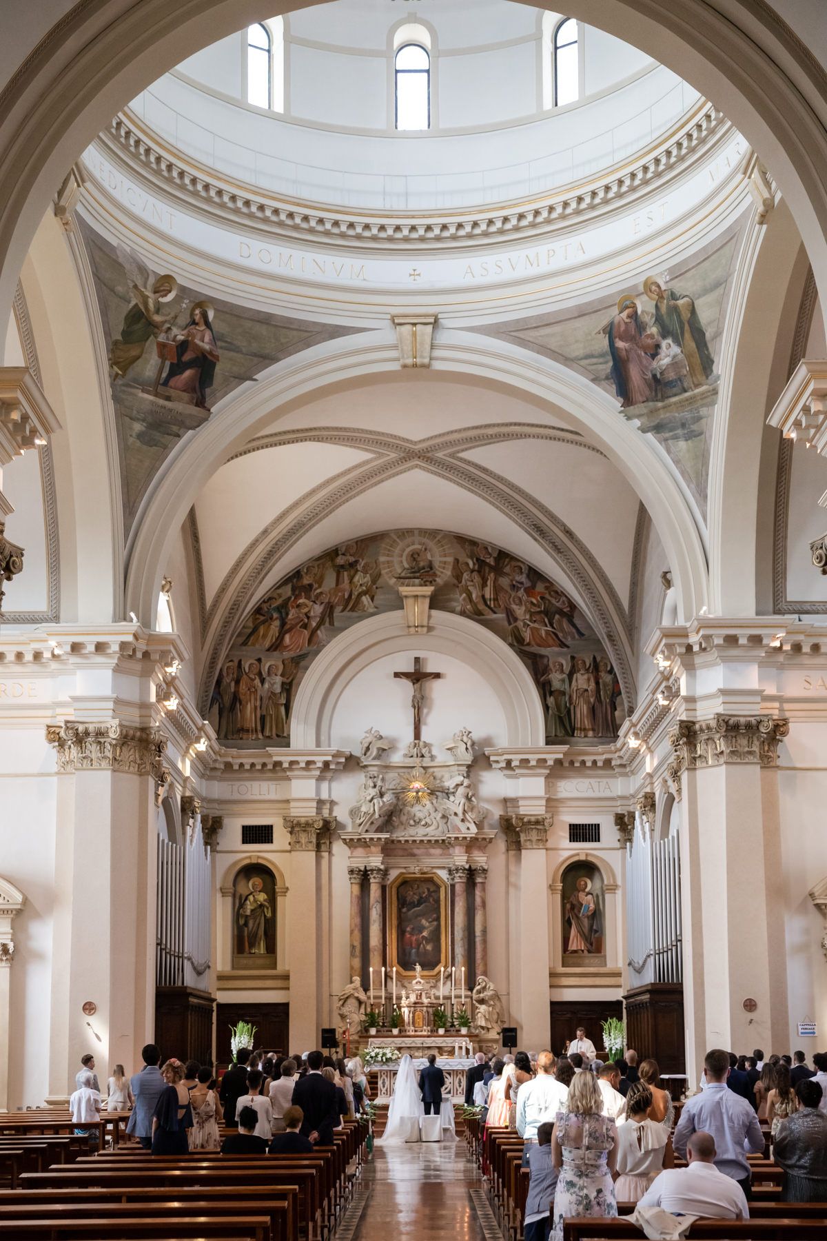 Ornate Catholic church interior with painted dome ceiling and classical architecture.