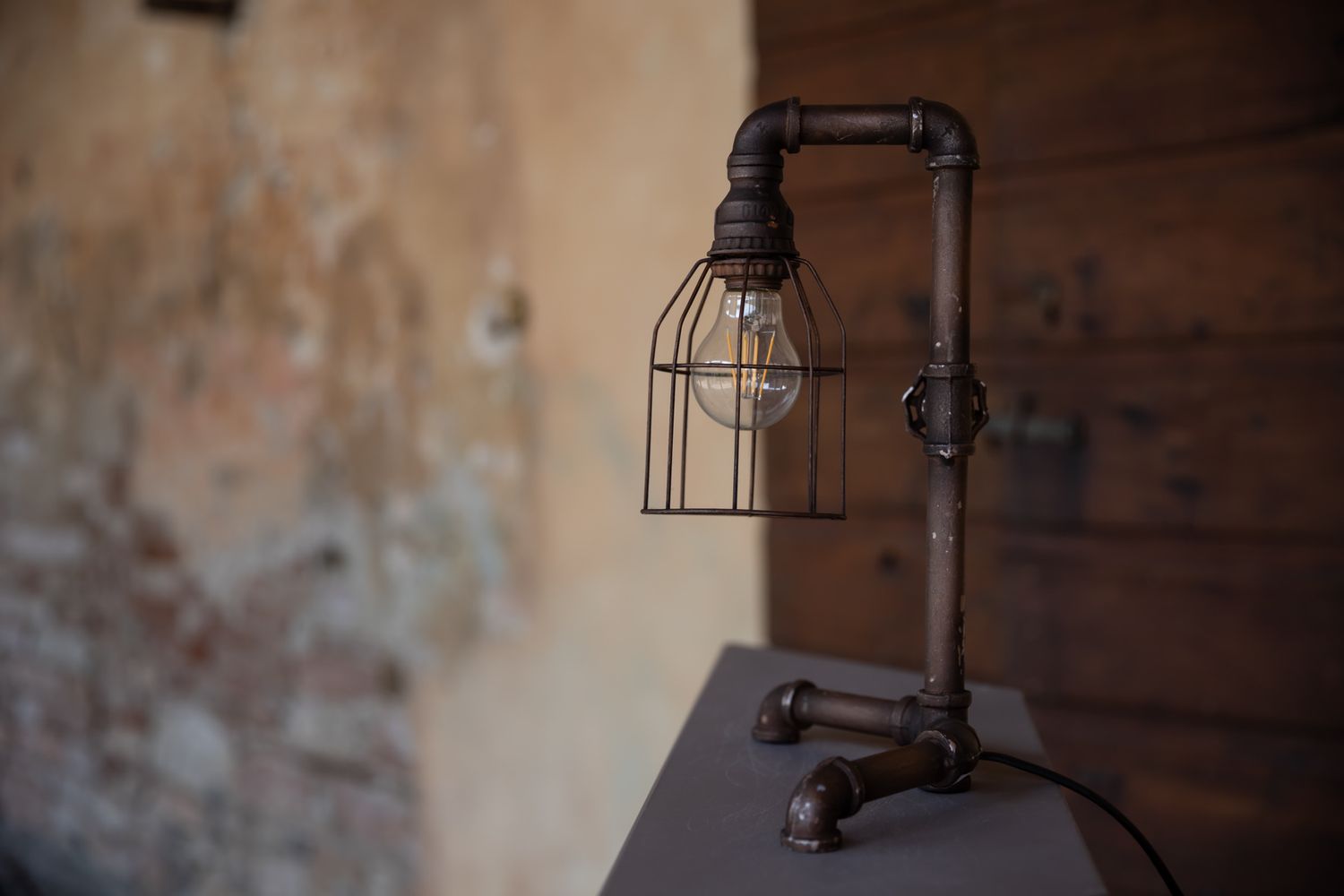 Industrial-style pendant lights hanging from wooden beams in a rustic interior space.
