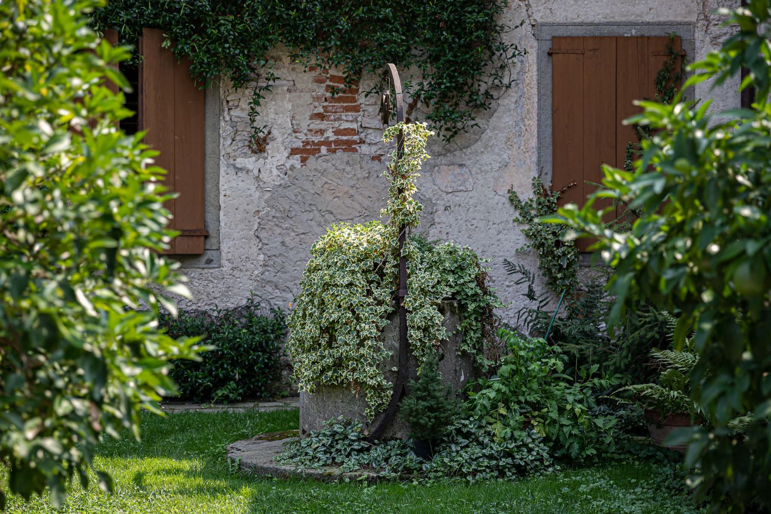 Exterior view of a stone building with green foliage and white stucco walls.