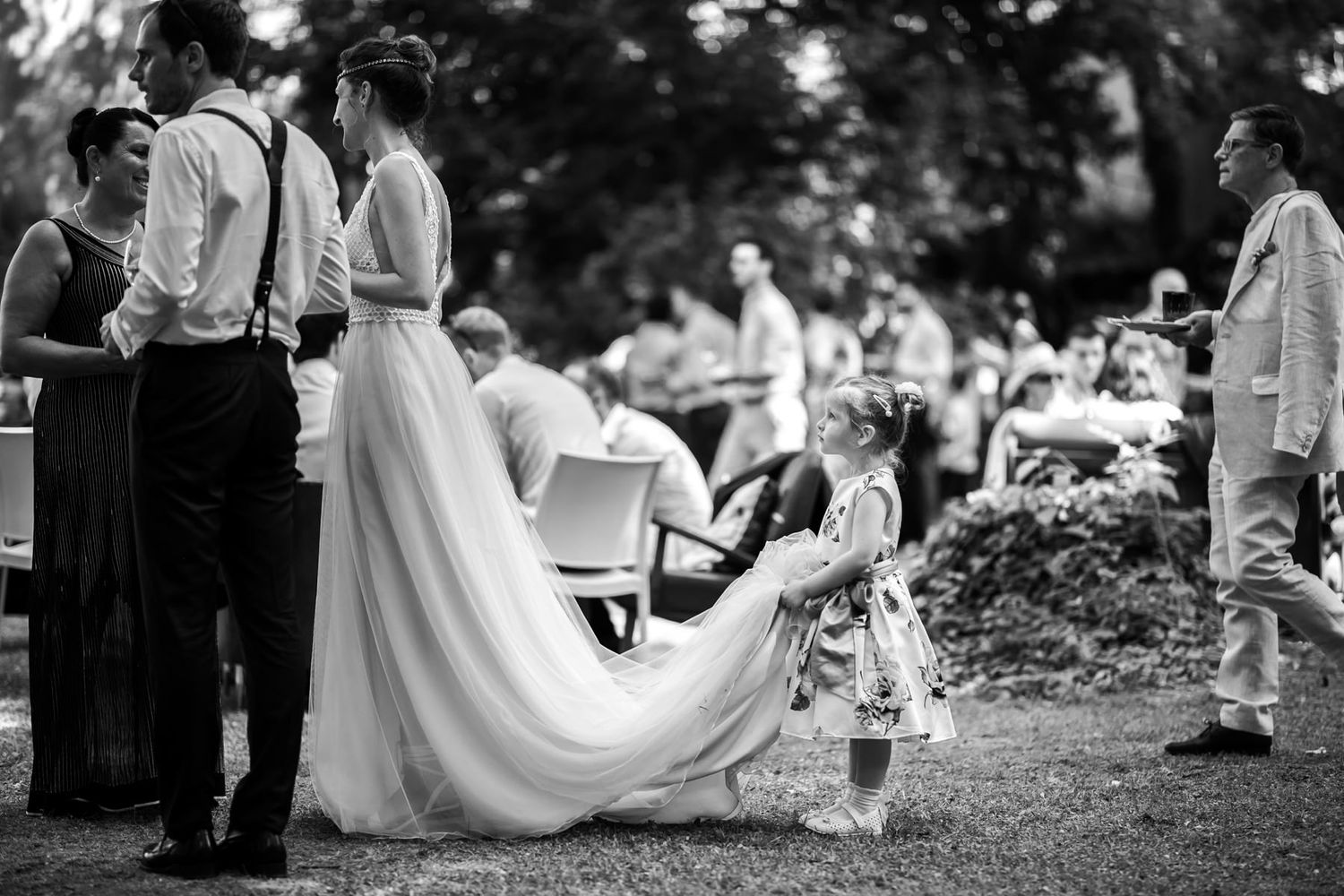 Black and white photograph of wedding guests gathered on a lawn during an outdoor celebration.