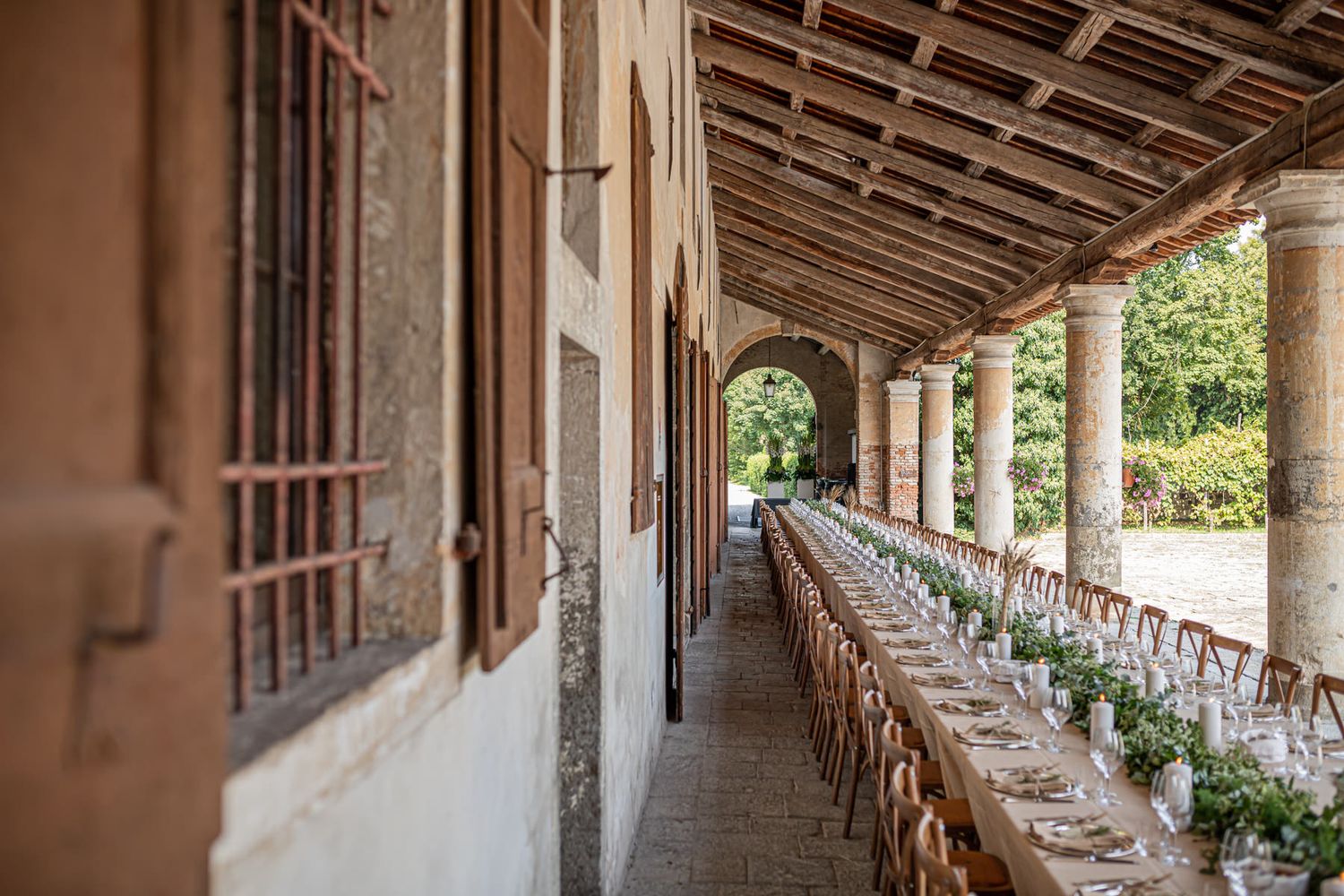 Long covered outdoor corridor with stone columns and wooden beams creating dramatic lighting and shadows.