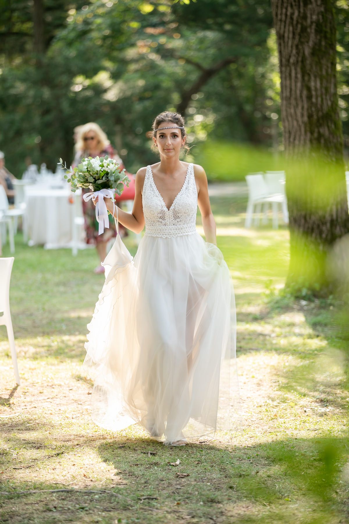 Wedding scene in a sunlit forest setting with white decor and natural elements.