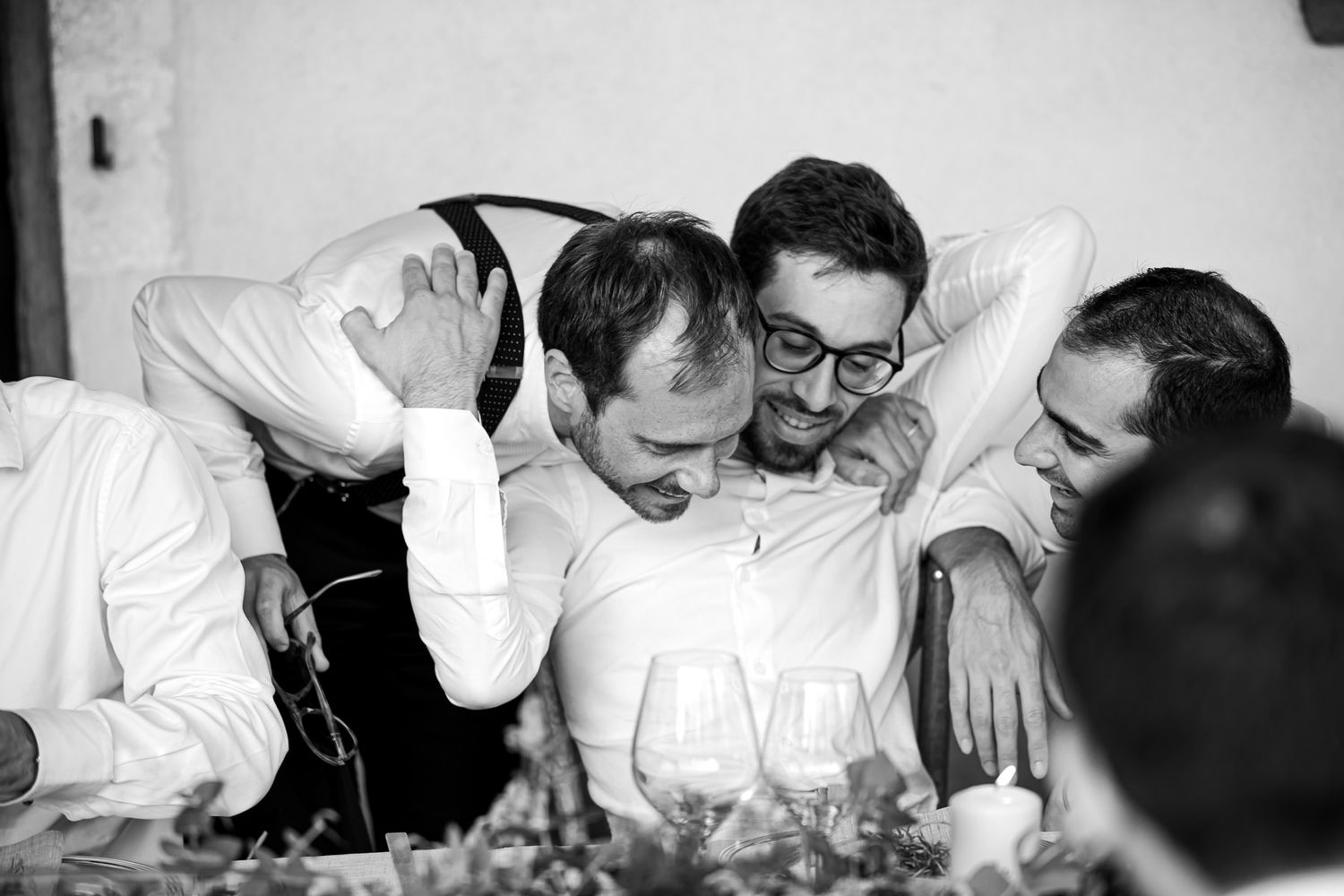 Black and white candid photo of wedding party sharing laughs together.
