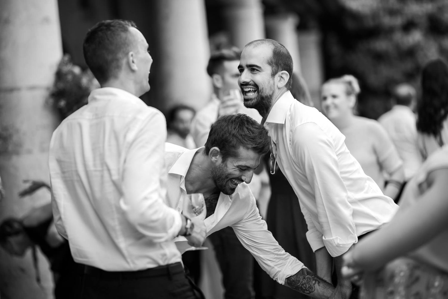 Wedding party members in white shirts dancing and celebrating together.