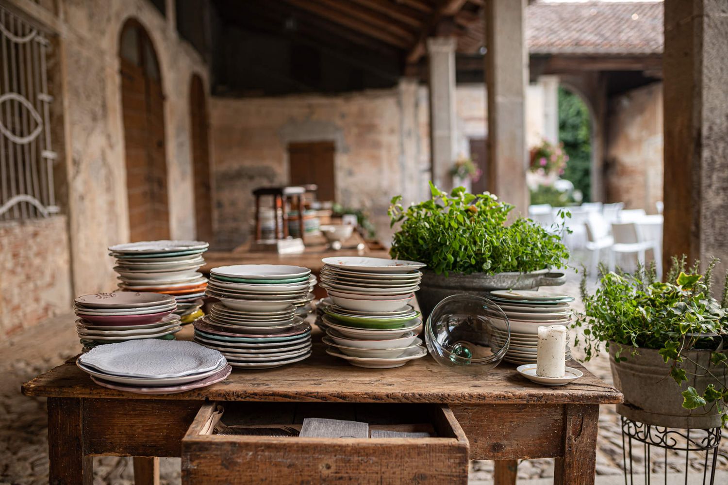 Rustic table setting with stacked plates and tableware in an outdoor venue.