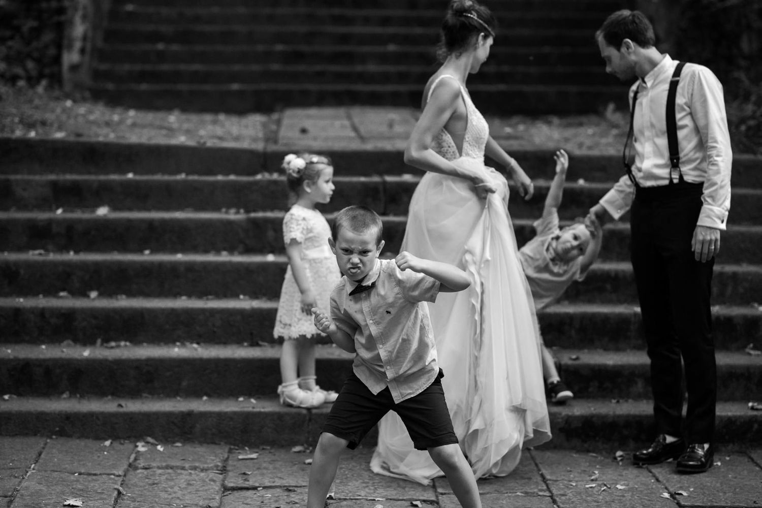 Wedding party members posing on stone steps in formal attire.