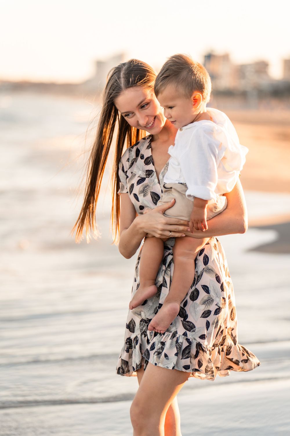 mother holding young son and smiling for beach family photos in alicante