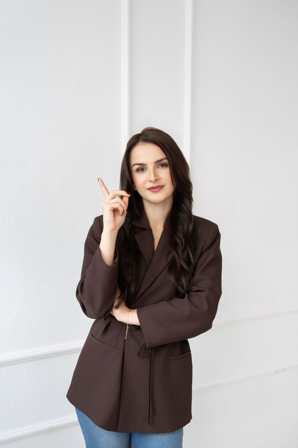 A woman in a brown blazer poses expressively against a white background in a professional photo series.