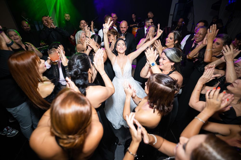 Energetic wedding reception dance floor scene with colorful lighting and celebrating guests.