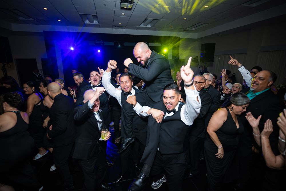 Lively dance floor celebration with party guests and colored lighting at wedding reception.