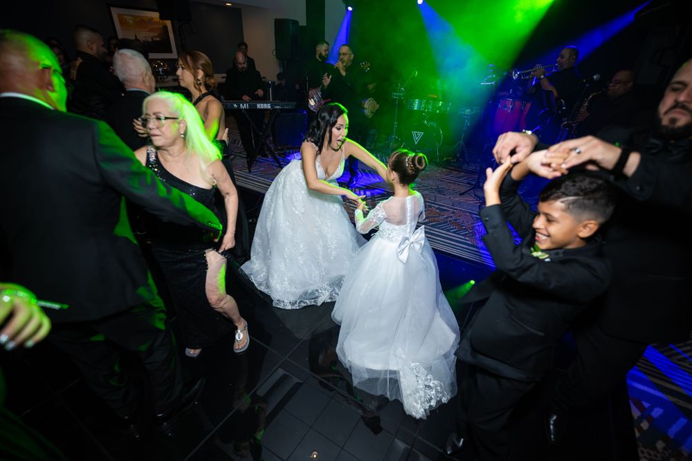 Dynamic dance party scene with guests celebrating at wedding reception under green lighting.
