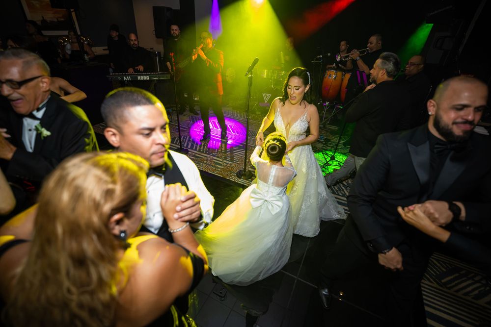 Wedding guests dance and celebrate on a colorful illuminated dance floor at an evening reception.