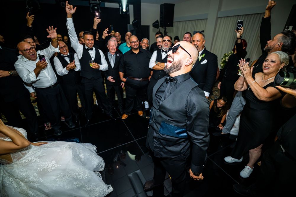 Wedding celebration with guests cheering and raising arms while dancing at reception.