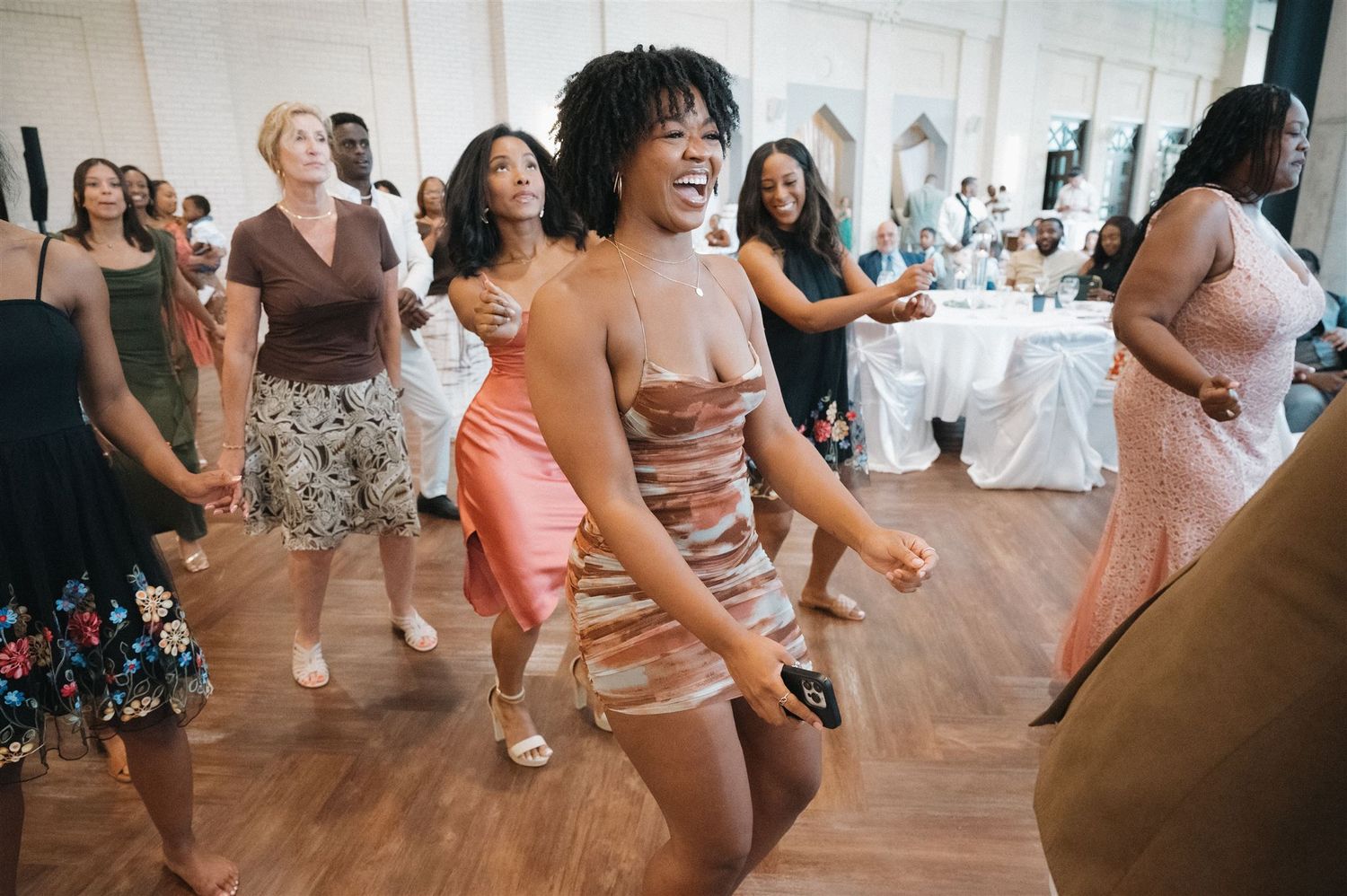 People dancing and having fun at a wedding reception on a wooden dance floor.