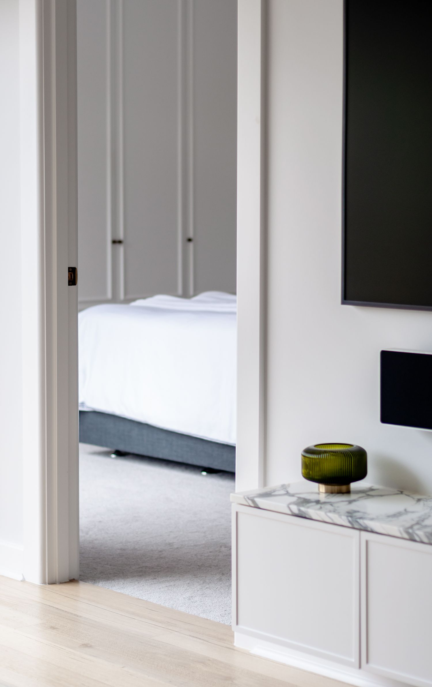 Glimpse into a bedroom through doorway with marble-topped console table in foreground.