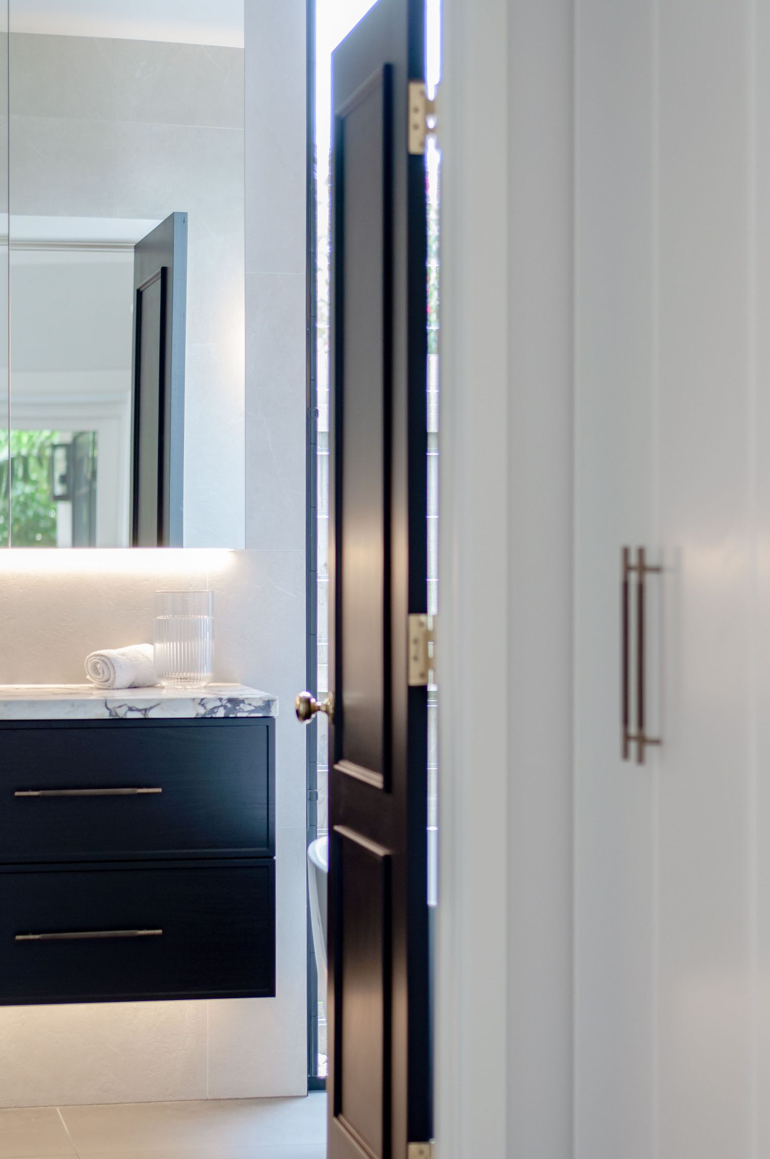 Interior doorway detail showing black door and modern black vanity with LED lighting.
