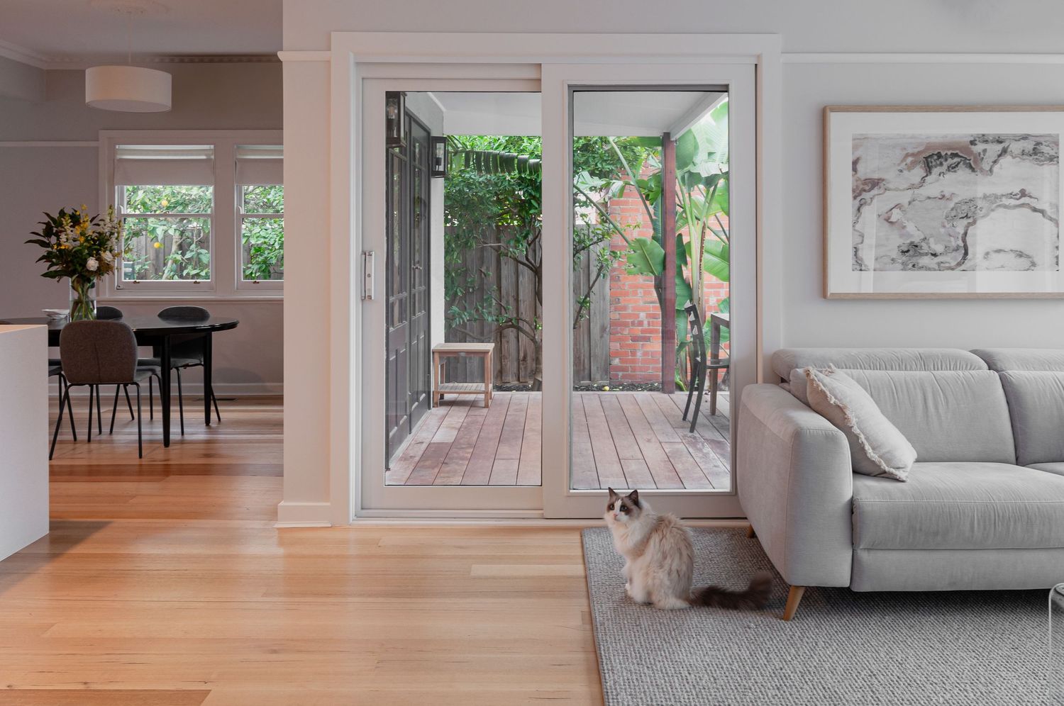 Bright living room with gray sofa and glass doors opening to outdoor wooden deck.