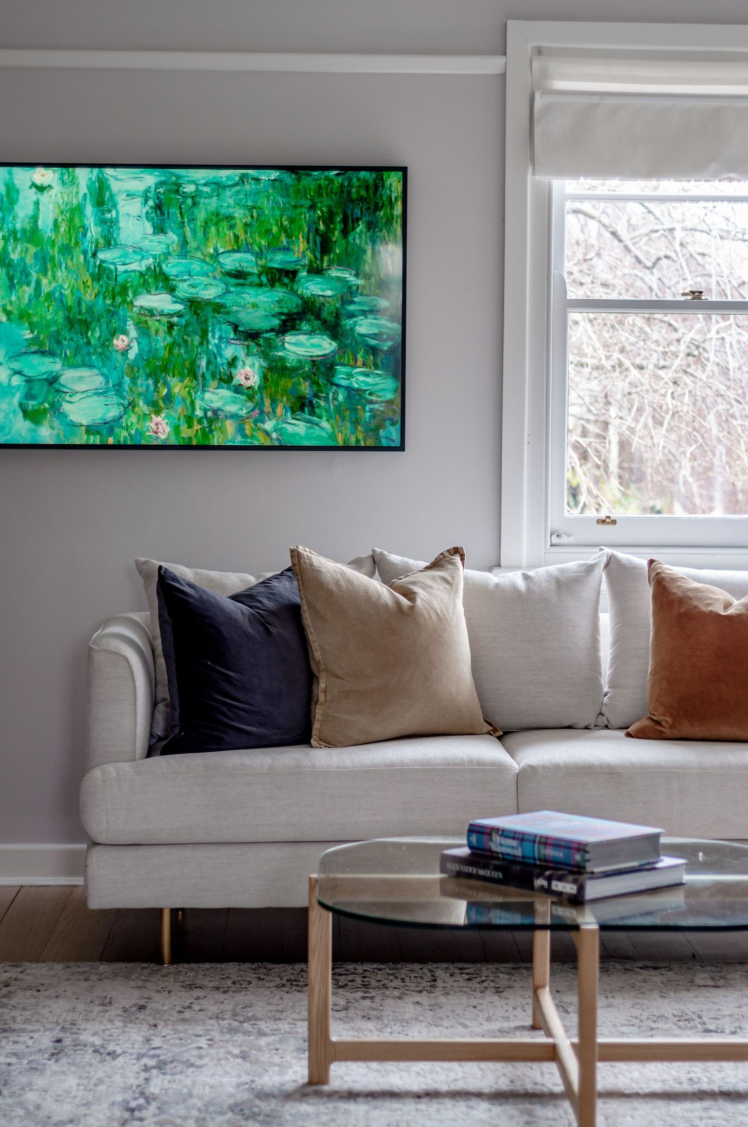 Modern living room with white sofa and green Monet-style artwork displayed above.