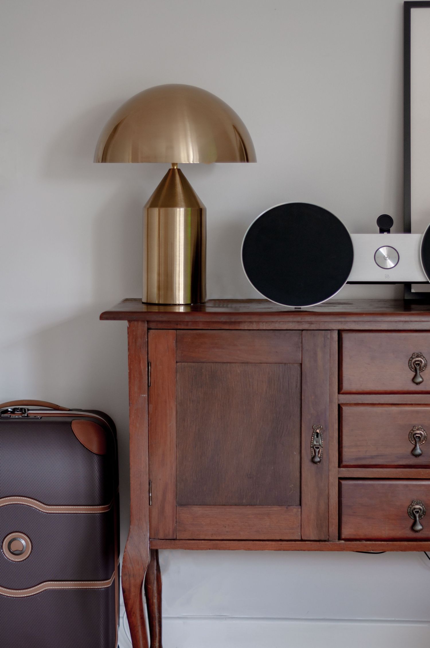 Vintage wooden cabinet with gold mushroom lamp and black speaker on top.