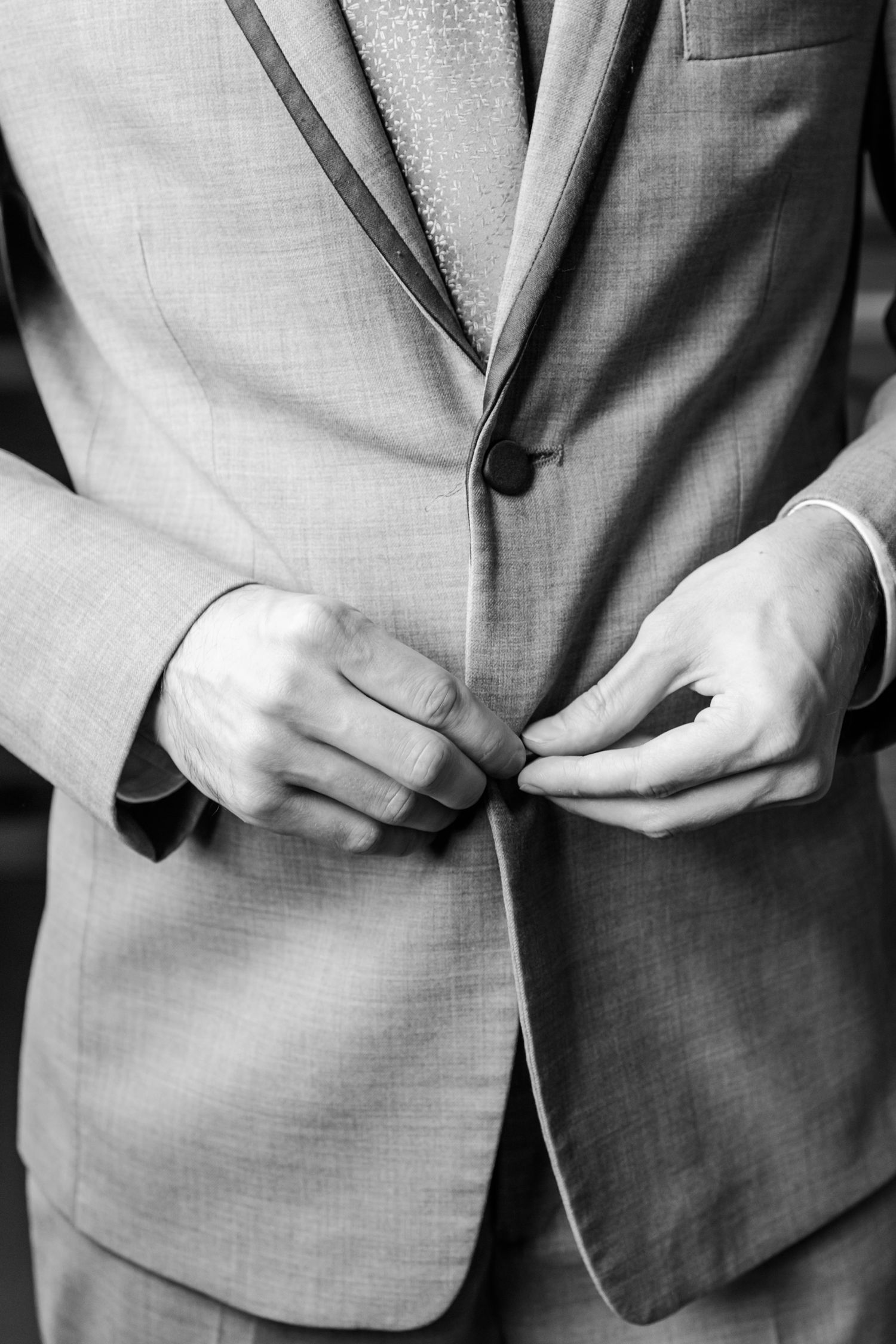 Close-up of gray suit jacket details showing refined tailoring and texture.