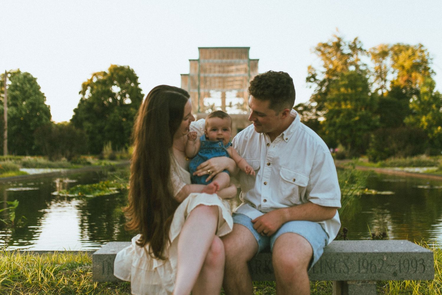 A tender family moment together by a serene lakeside at golden hour.