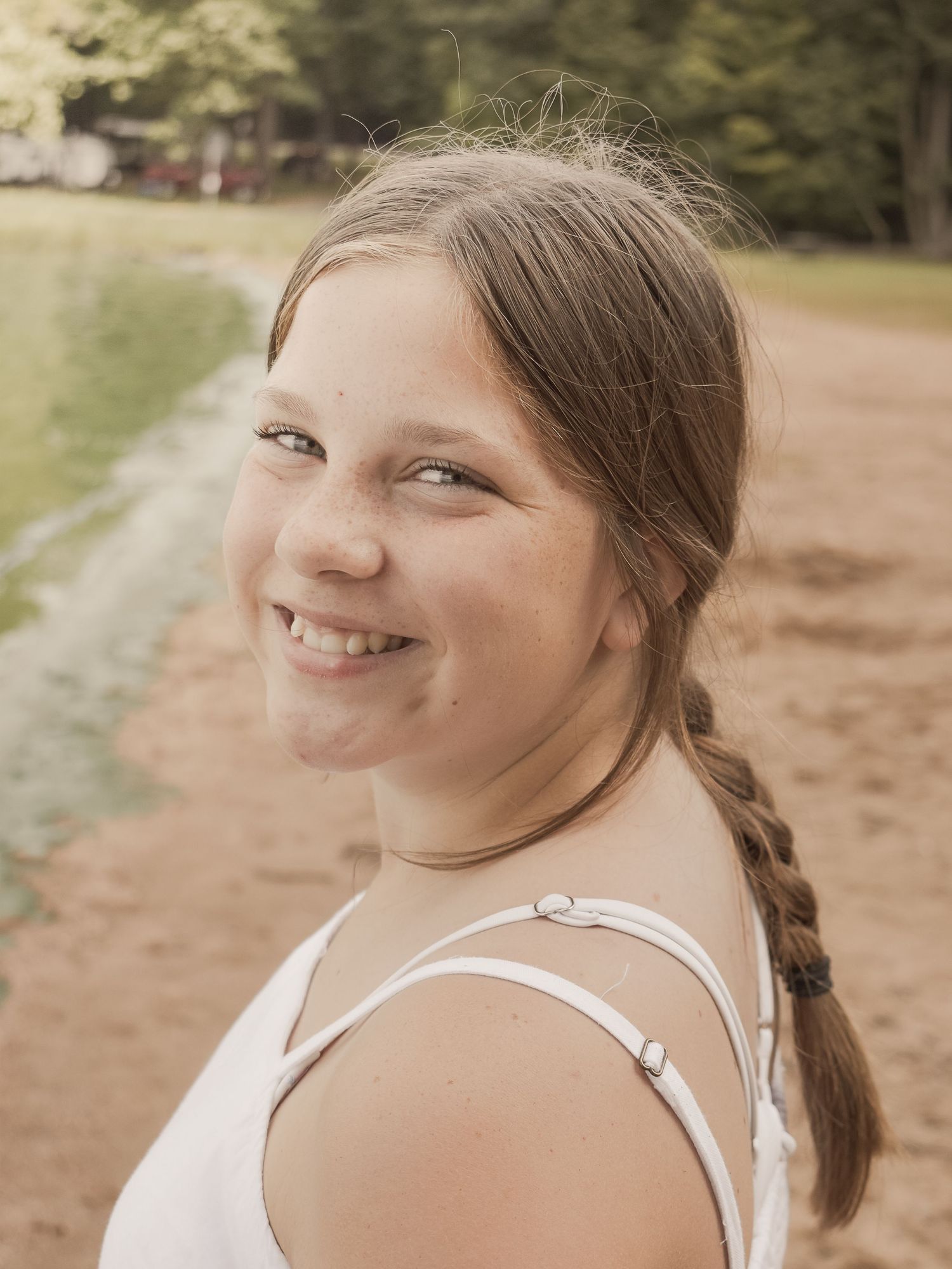 Photo of a young girl wearing a white dress, looking over the water contemplatively.  Blue Onion Photography.
