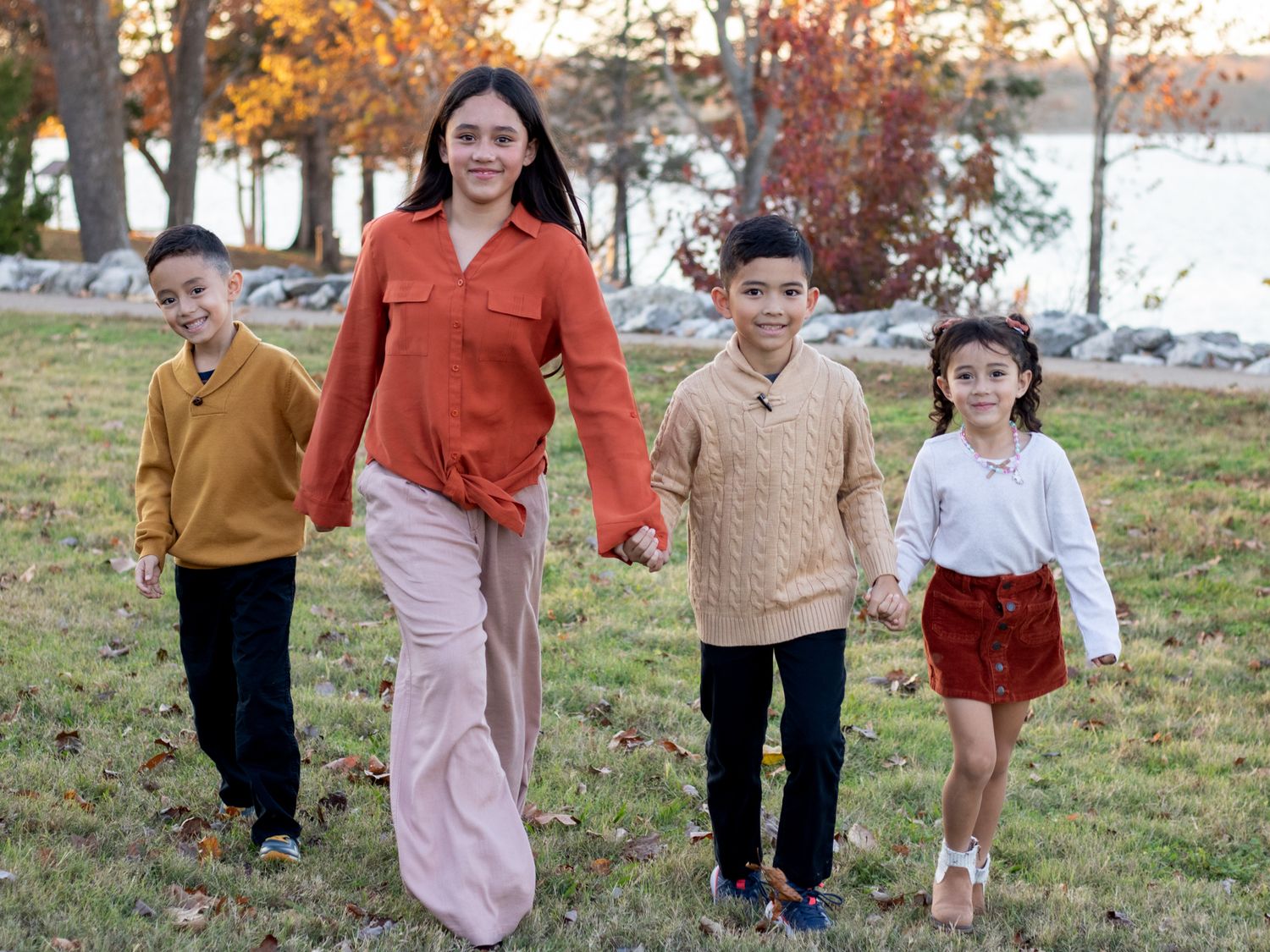 Kids smiling running towards camera by the lake.