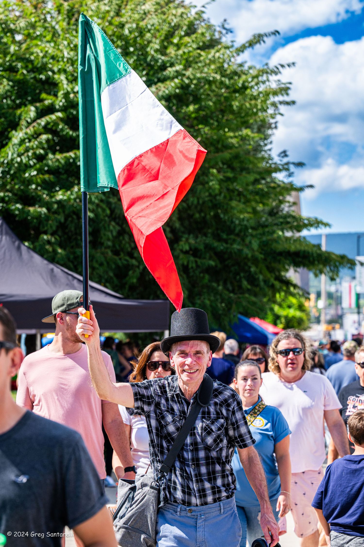 Festival attendees celebrating with Mexican flags under blue summer skies.