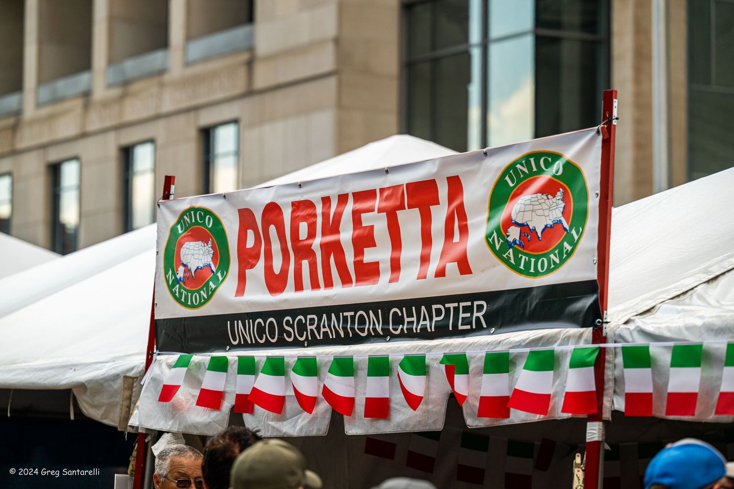 UNICO Scranton Chapter Porketta banner at an outdoor Italian festival with white tents in background.