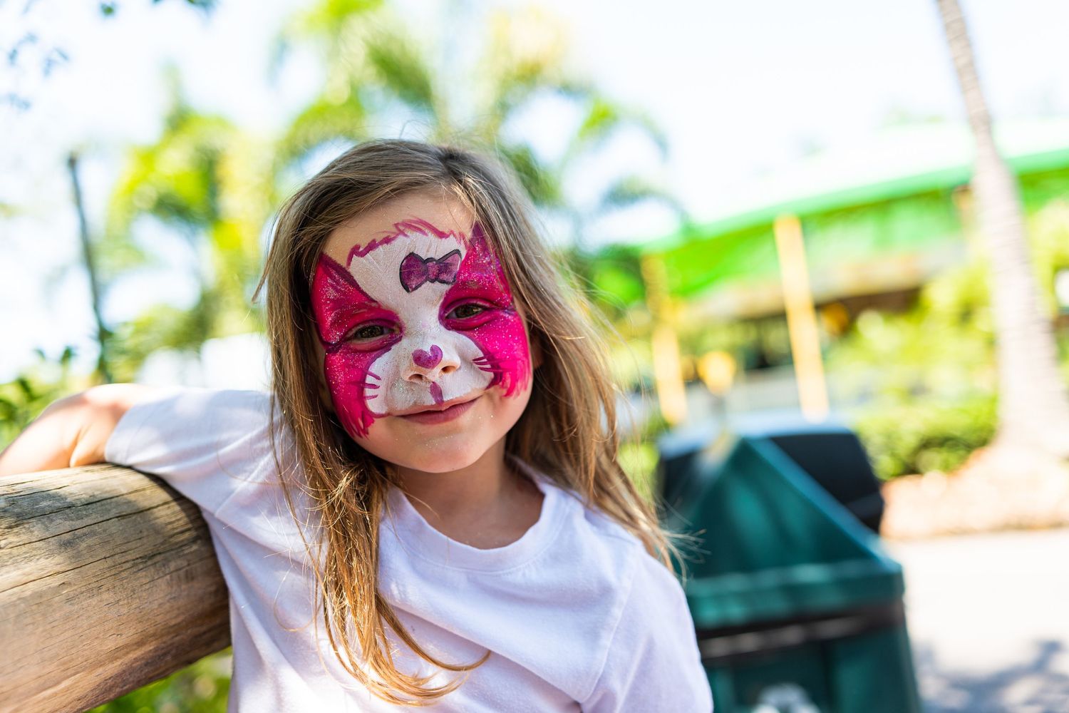 Children wearing colorful face paint and smiling during an outdoor event.