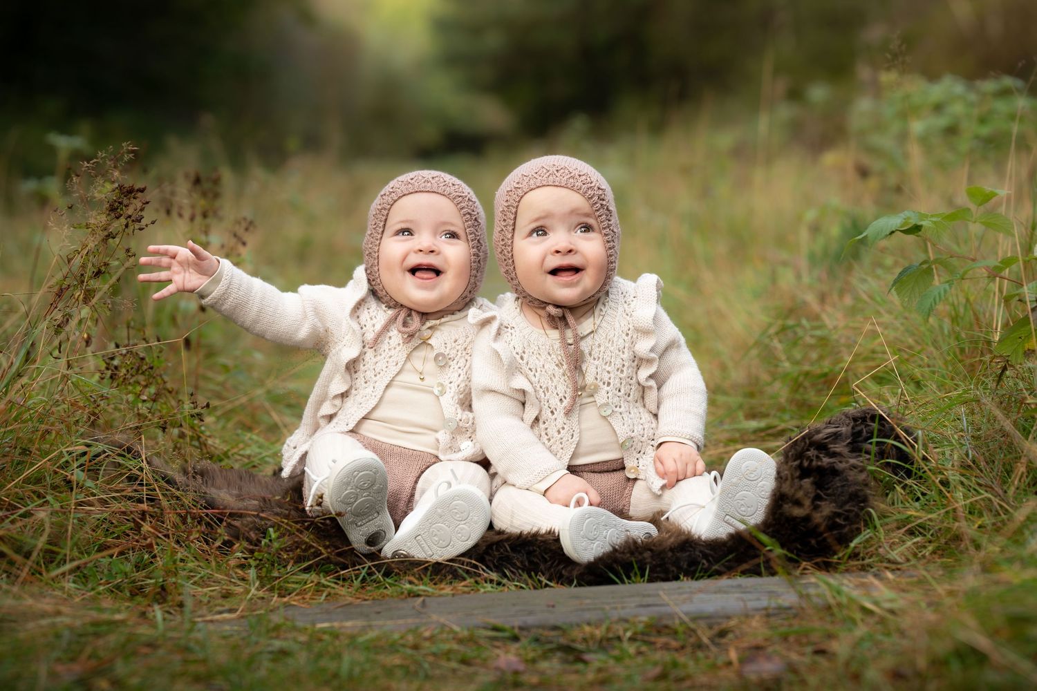 Utendørs babyfotografering høst og vinter - nydelige, blide tvillinger smiler i skogen