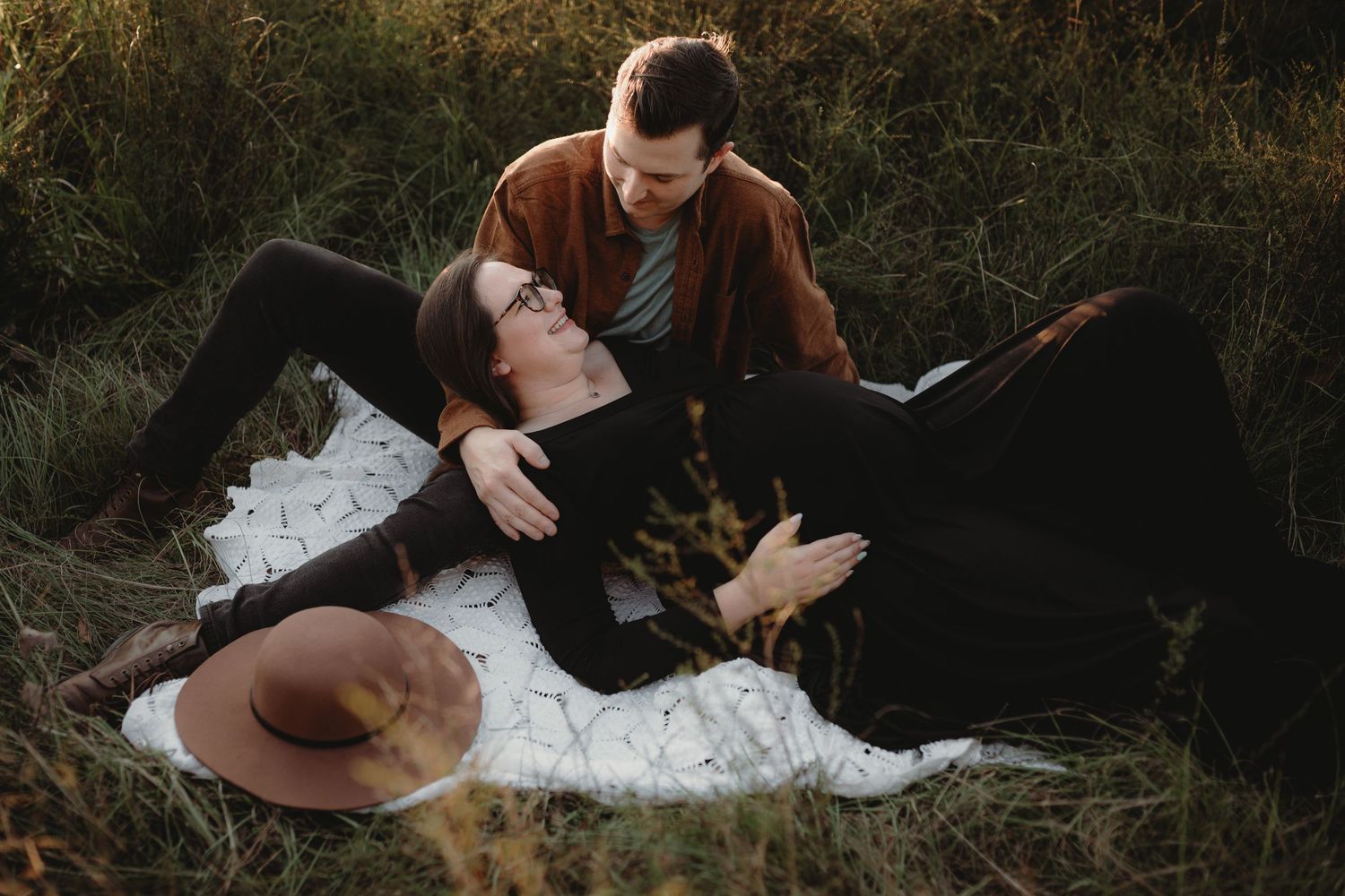 Romantic couple's portrait session in tall grass during golden hour.
