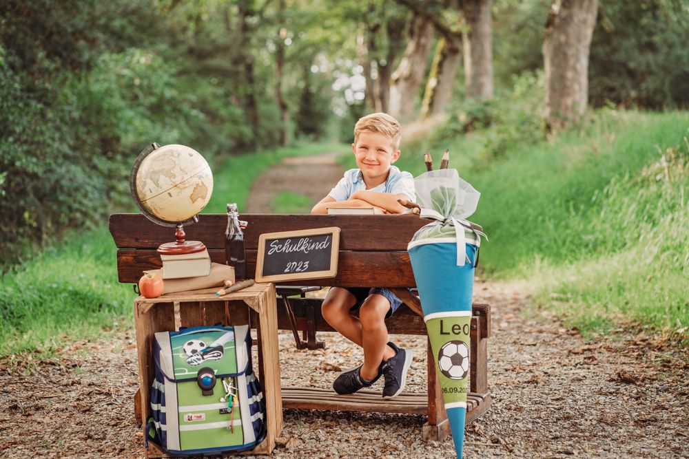 Vintage school desk setup outdoors with globe and educational props on forest trail.