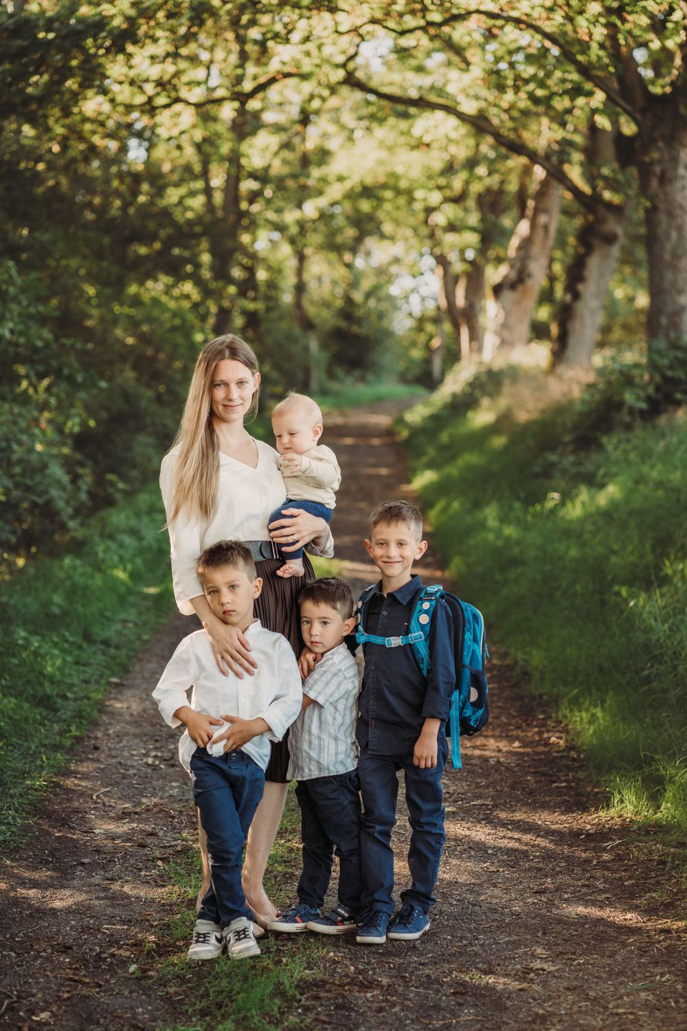 Family standing together on forest path with backpack for back to school photo.