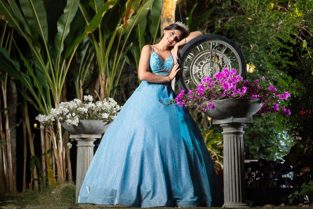 A flowing blue ballgown photographed against lush tropical foliage and palm trees.