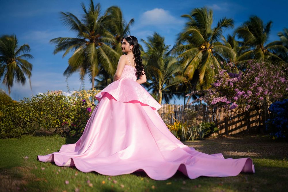 A pink princess ballgown photographed against palm trees and blue tropical skies.