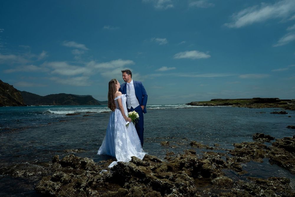 Scenic oceanside wedding portrait with dramatic coastline and blue skies.