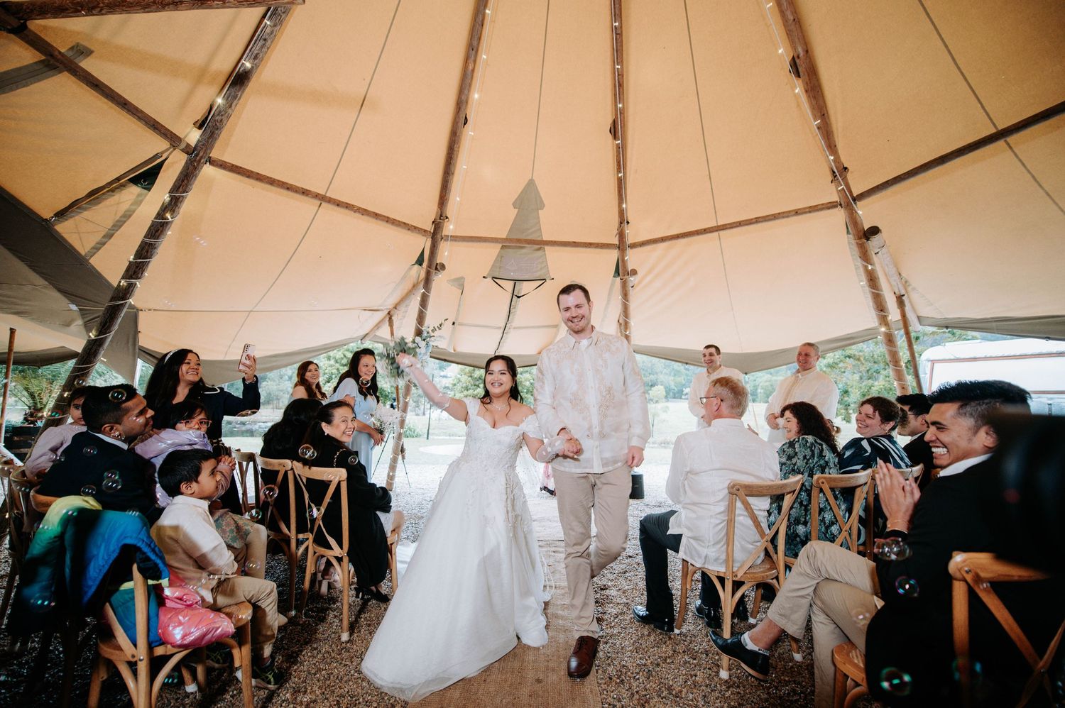 Wedding celebration inside a circular tent as guests cheer during the recessional.